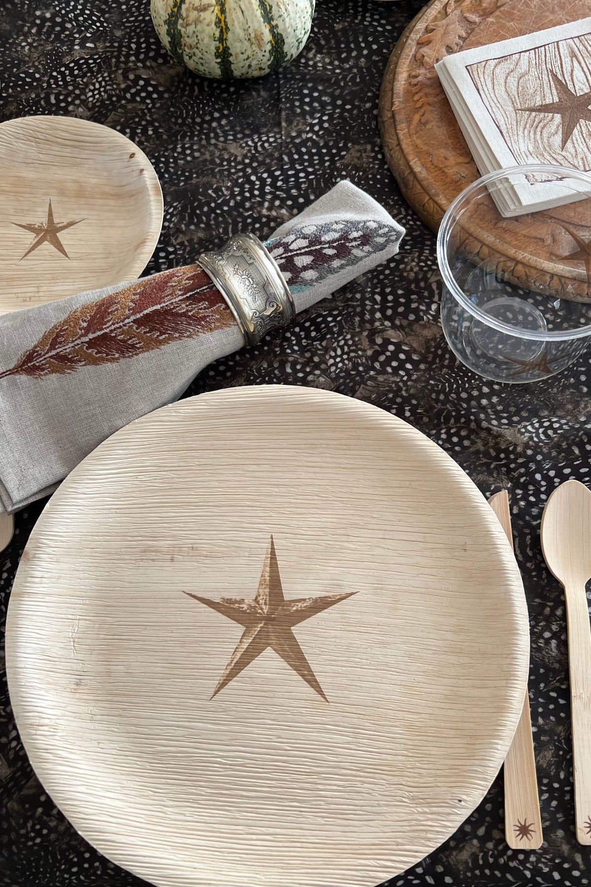 Table setting with wooden plates, cutlery, and decorative items on a textured surface.