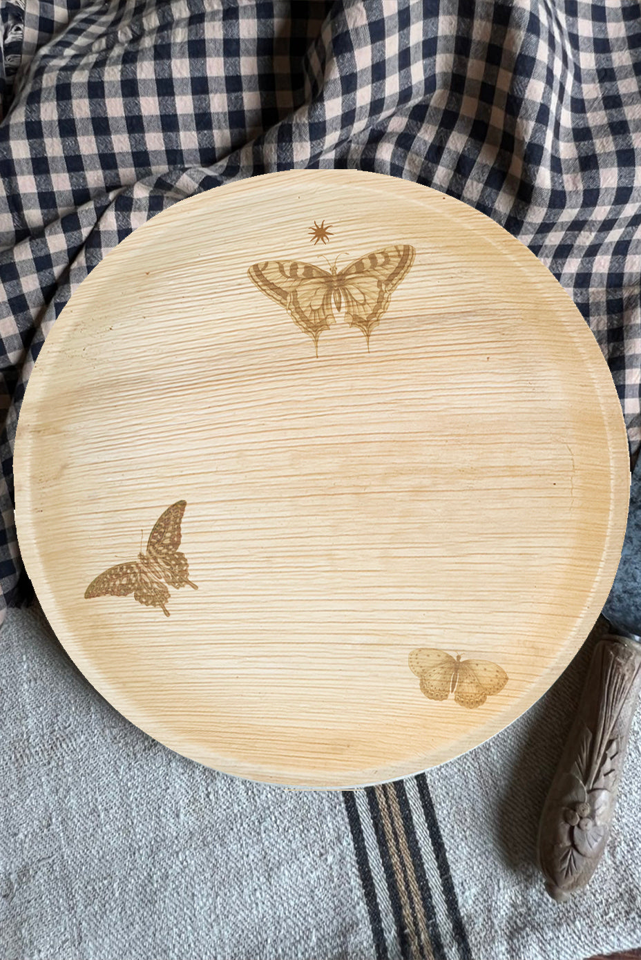 maaterra compostable palm leaf plate with butterfly wreath design on a gingham tablecloth