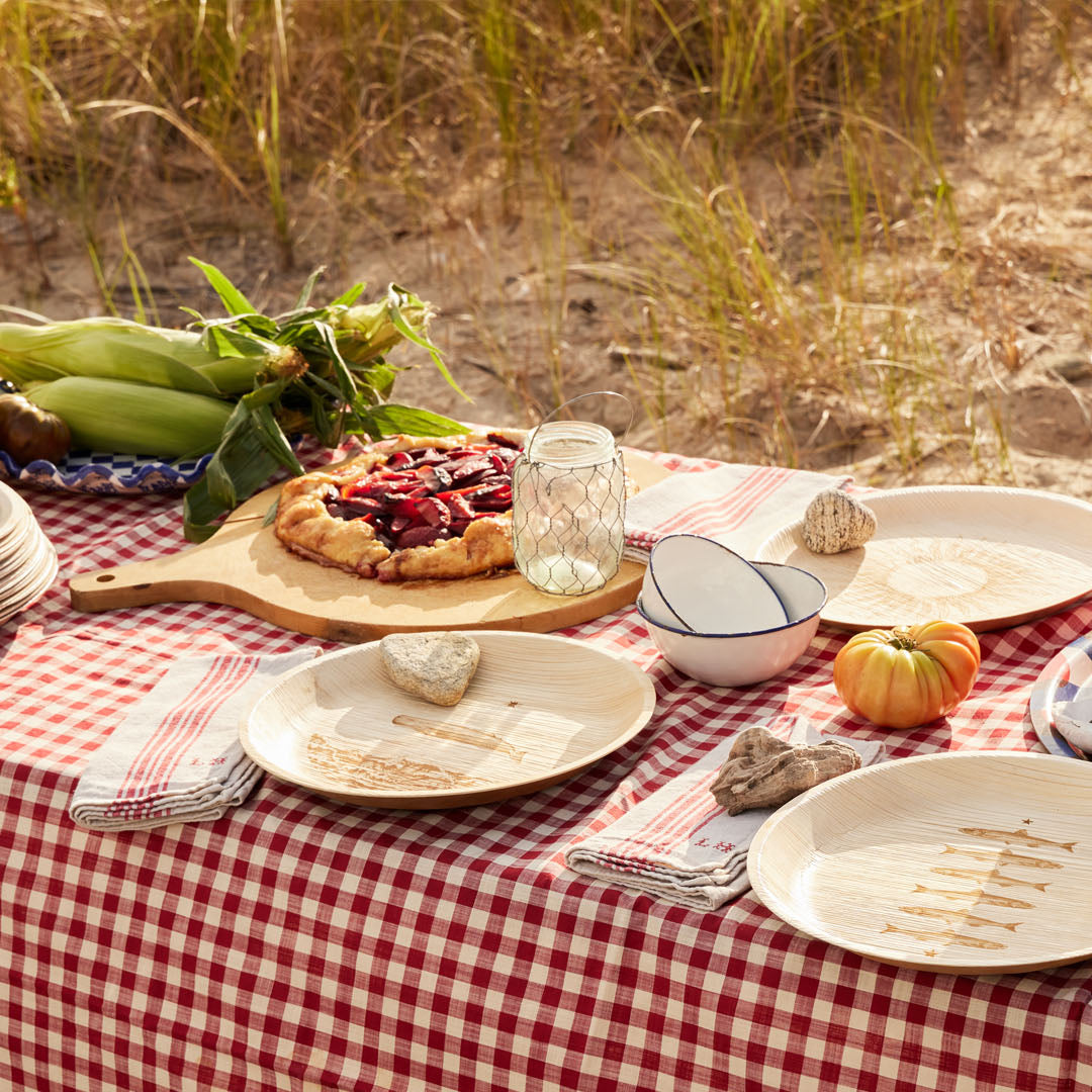 maaterra compostable palm leaf plates on a table at a beach.