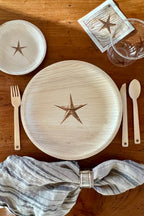 Dining table setting with star-shaped cutlery and plates on a wooden surface.
