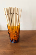 Vintage-style glass filled with bamboo straws on a wooden surface