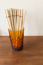 Vintage-style glass filled with bamboo straws on a wooden surface