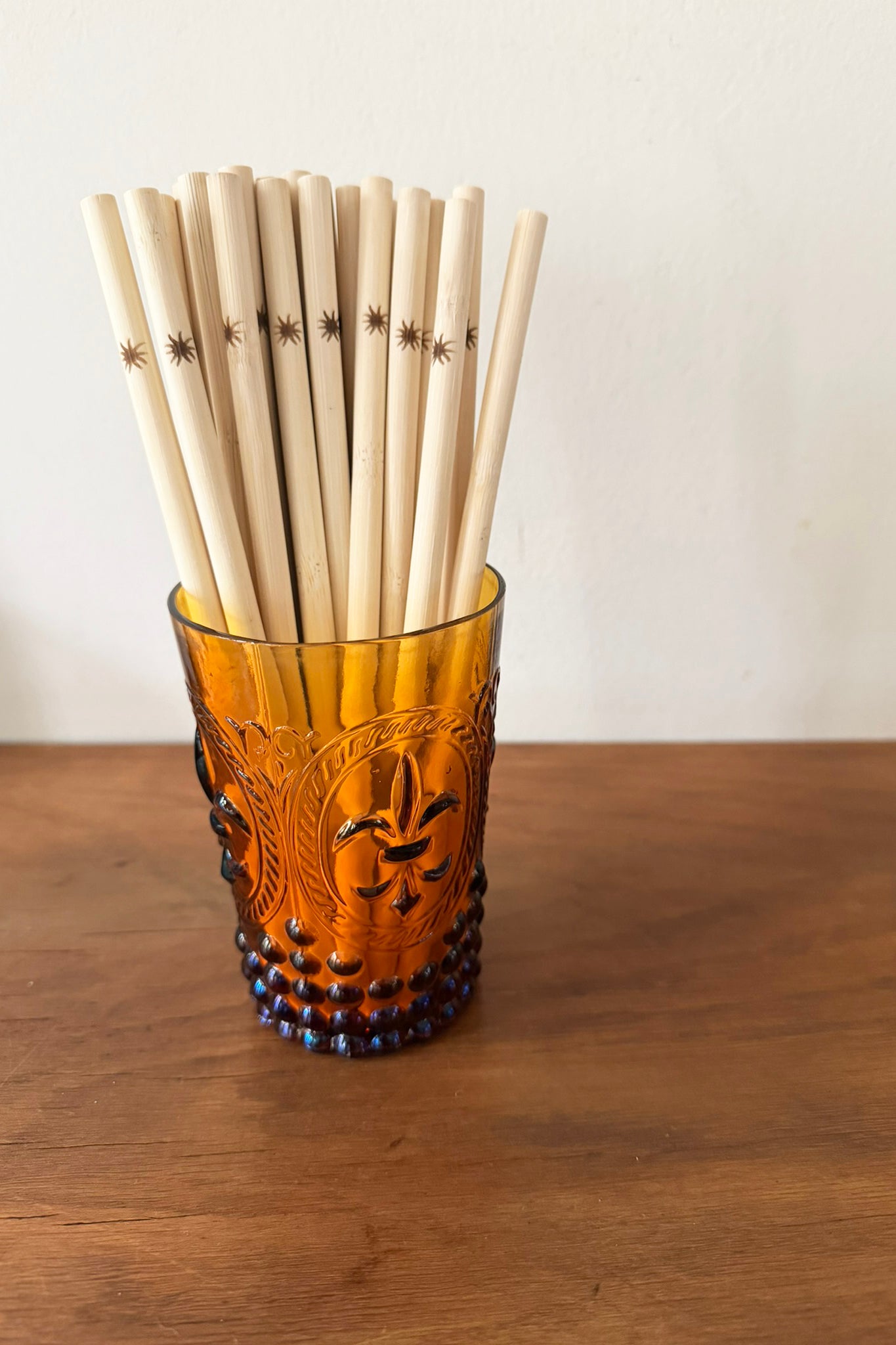 Vintage-style glass filled with bamboo straws on a wooden surface