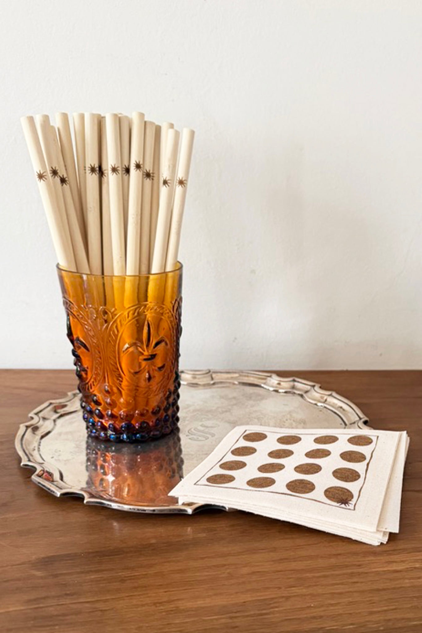 Amber glass with bamboo straws on a silver tray with a white napkin