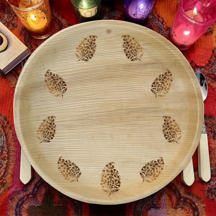 maaterra compostable palm leaf plate with block print wreath design on a red tablecloth with candles