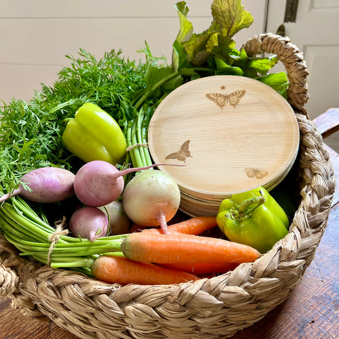 maaterra compostable palm leaf plate with butterfly wreath design in a basket with vegetables