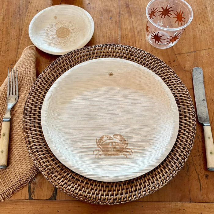 maaterra compostable palm leaf plate with crab design on a woven charger