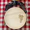 maaterra compostable palm leaf plate with grapes design on a gingham tablecloth