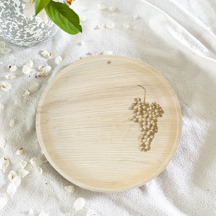 maaterra compostable palm leaf plate with grapes design on a white tablecloth