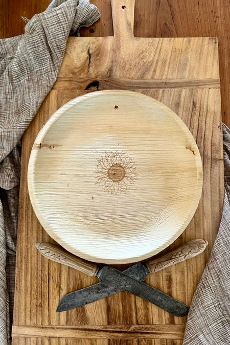 maaterra compostable palm leaf plate with sunflower design on a bread board