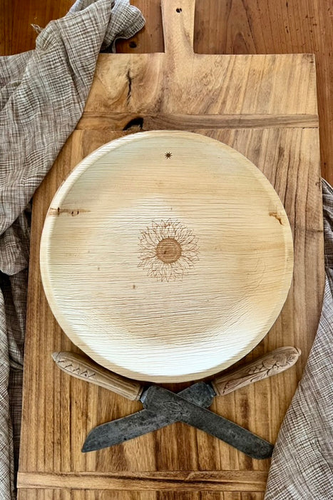 maaterra compostable palm leaf plate with sunflower design on a bread board