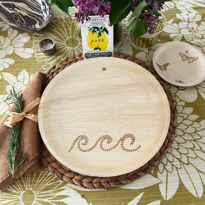 maaterra compostable palm leaf plate with waves design on a flower tablecloth
