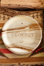 Wooden plate with 'COOKOUT' engraving on a patterned fabric background