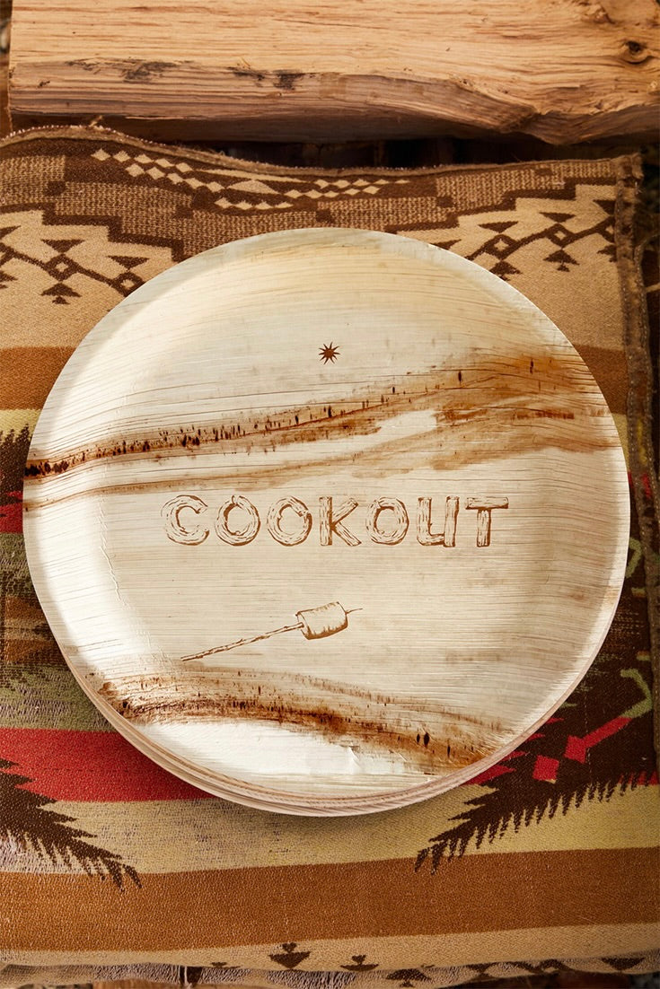 Wooden plate with 'COOKOUT' engraving on a patterned fabric background
