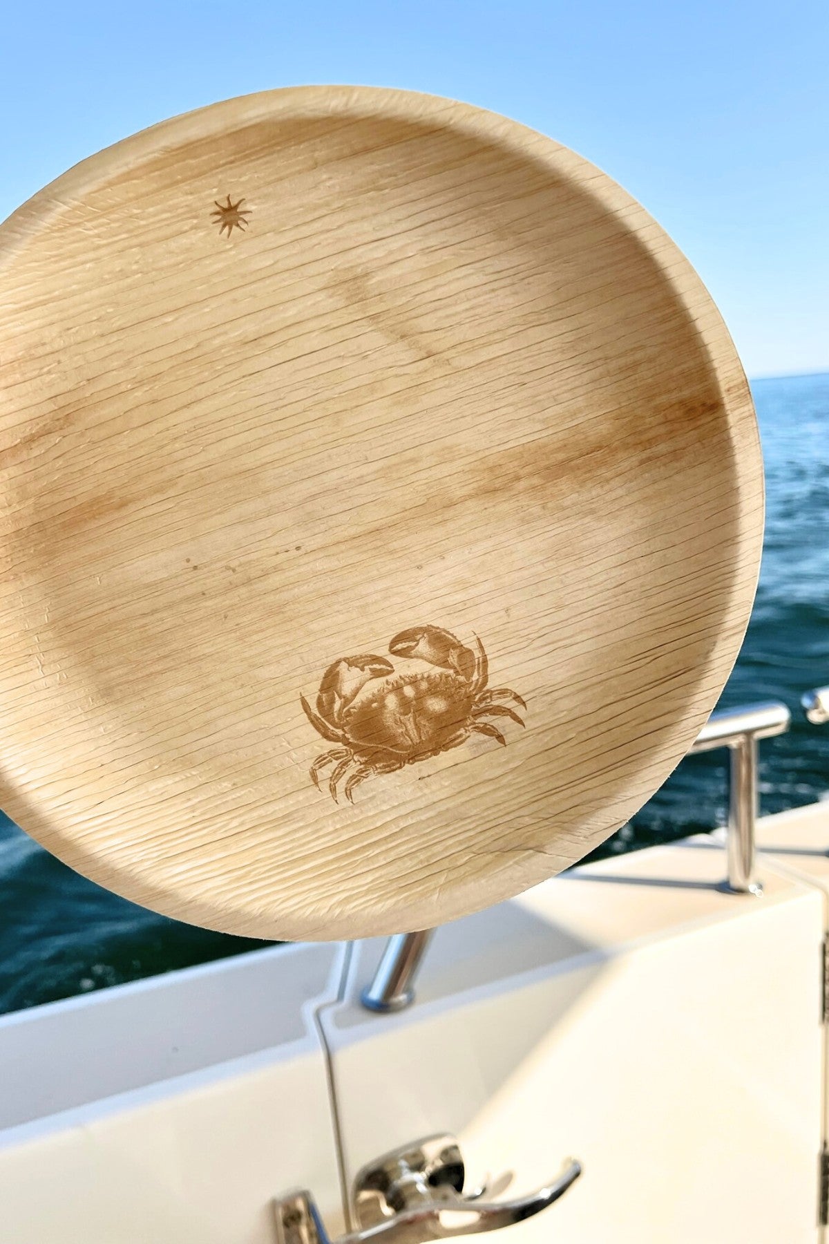 maaterra compostable palm leaf plate with a crab design on a boat with an ocean view
