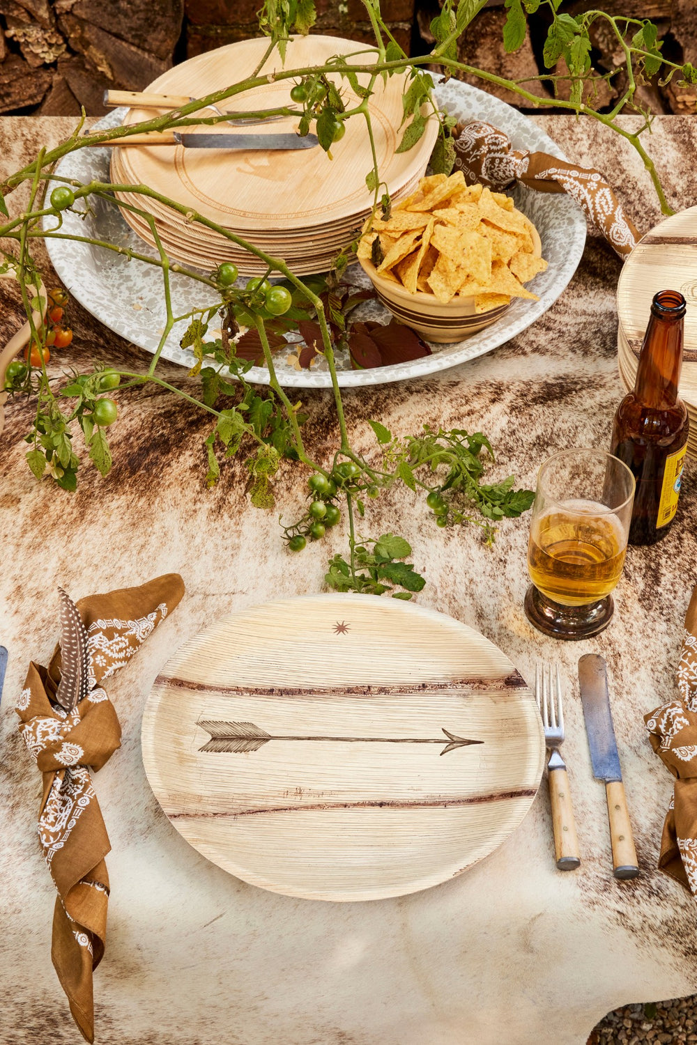 Western-themed dining table setup, including a wooden plate with an arrow design, tortilla chips, and a beer bottle.