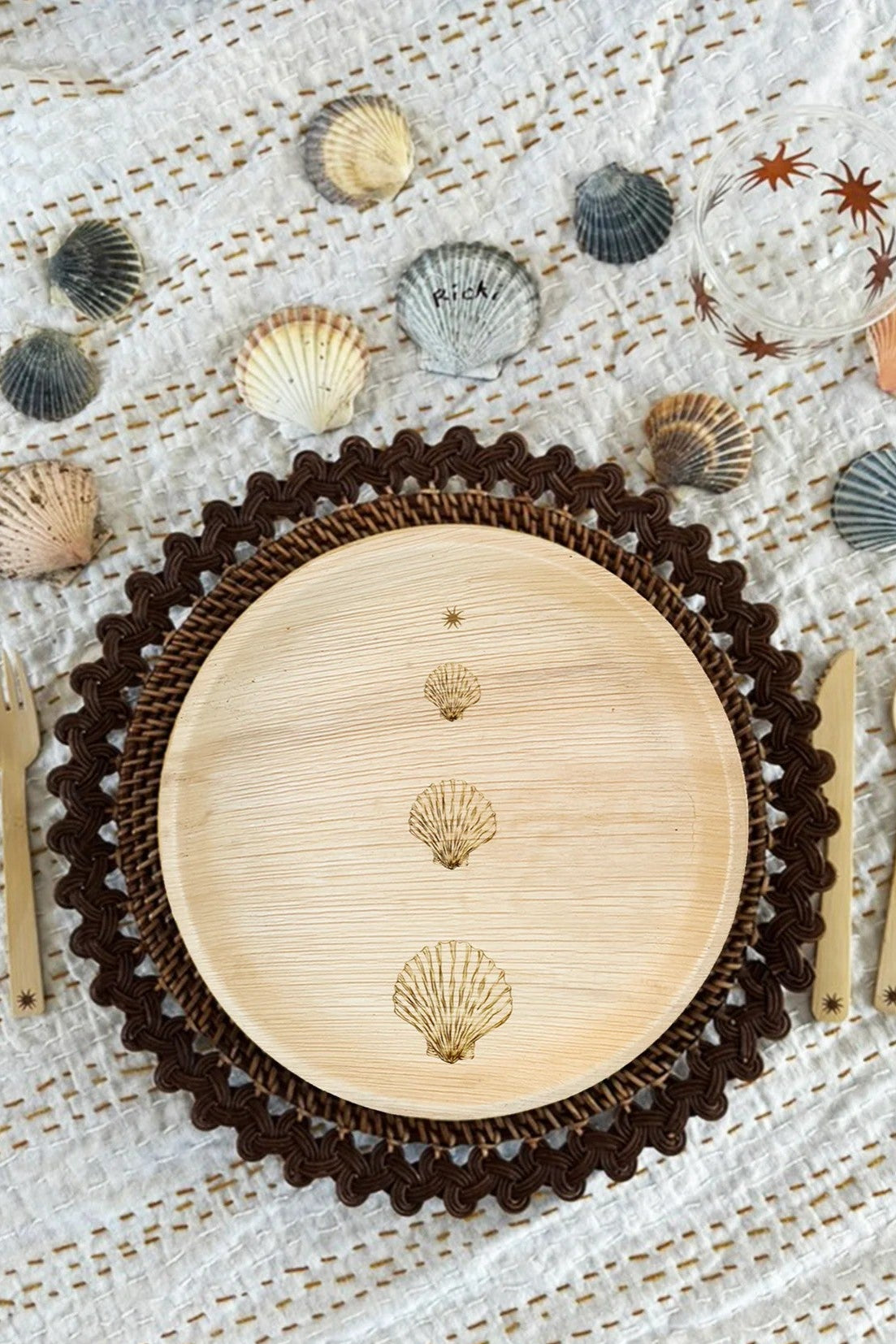 Wooden plate with shell design on a textured surface with seashells and starfish.