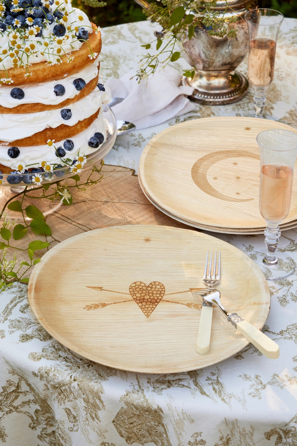 maaterra compostable palm leaf plate with stone heart engraving on a table with wedding themed table cloth and wedding cake. 