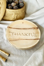 maaerra compostable palm leaf plate with engraving "thankful" on a white tablecloth.