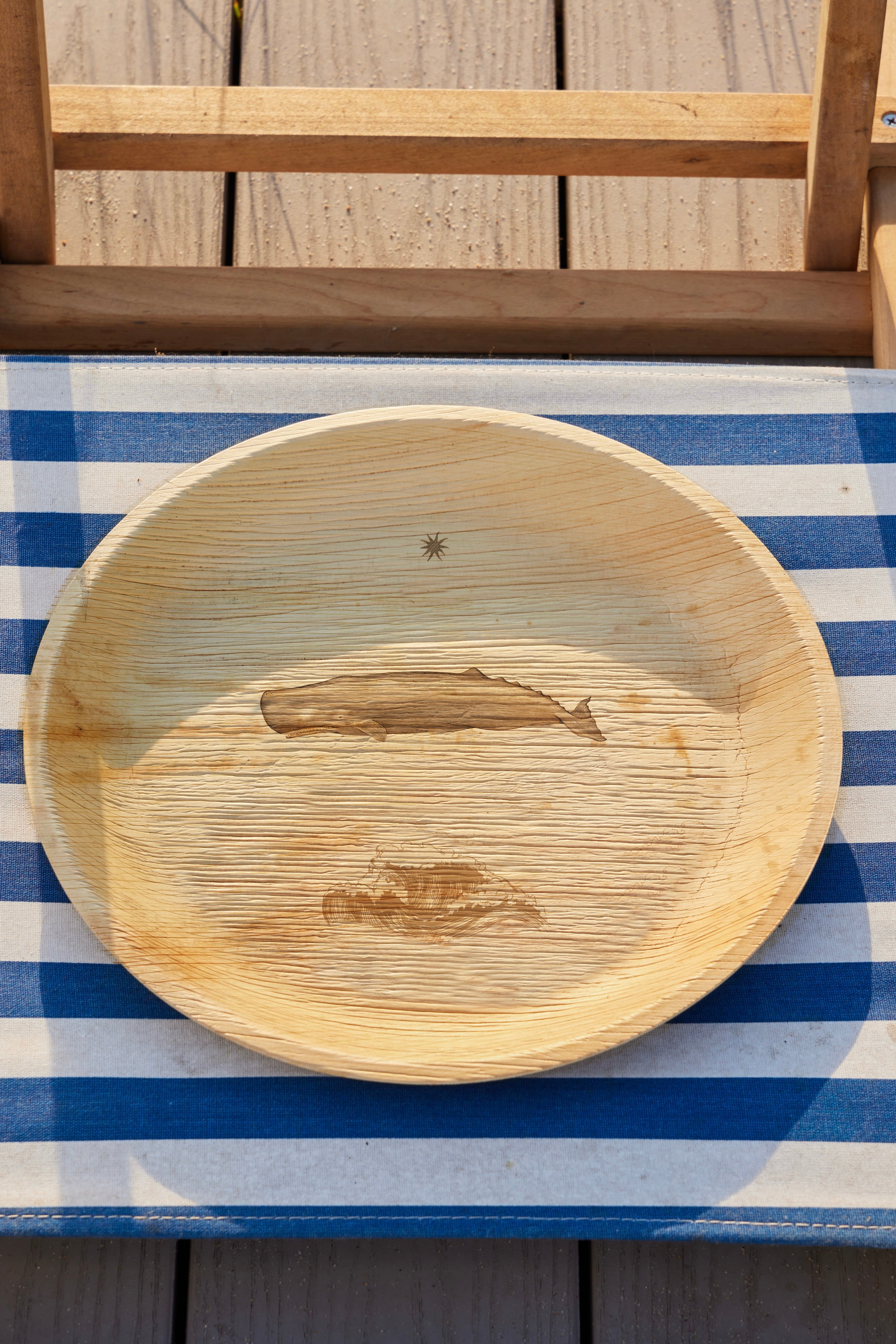 maaterra palm leaf plate with whale tale design on a boardwalk.
